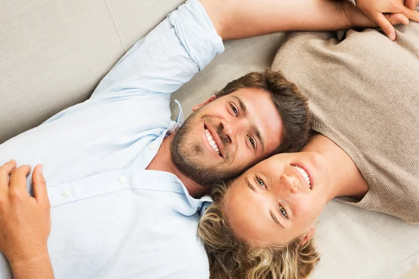 Jovem casal feliz em casa no sofá — Fotografia de Stock