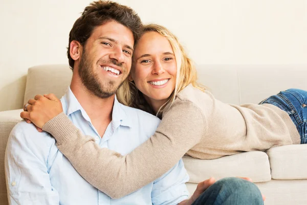 Jovem casal feliz em casa no sofá — Fotografia de Stock