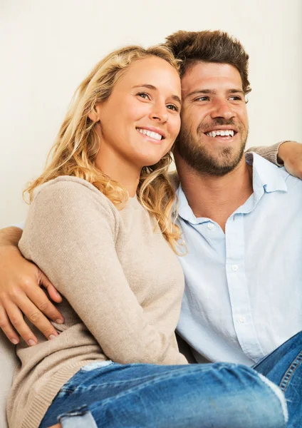 Jovem casal feliz em casa no sofá — Fotografia de Stock