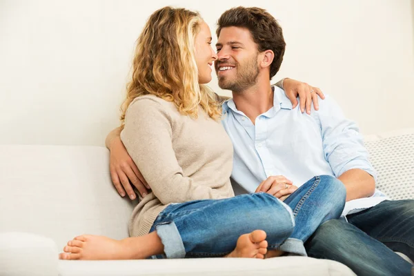 Jovem casal feliz em casa no sofá — Fotografia de Stock