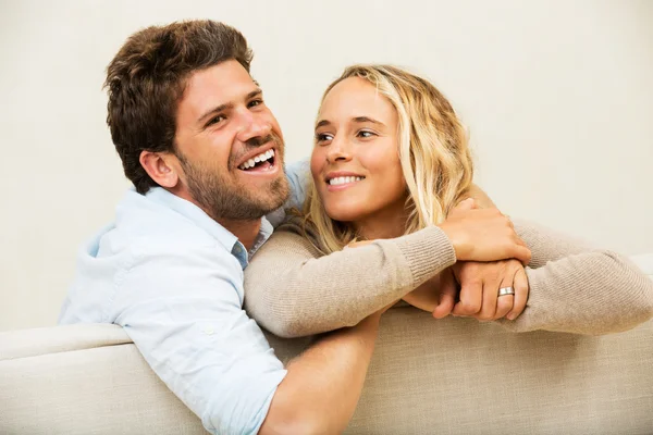 Jovem casal feliz em casa no sofá — Fotografia de Stock