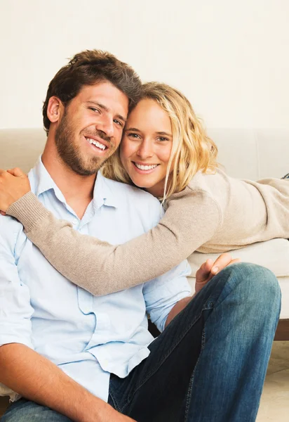 Happy young couple at home on sofa — Stock Photo, Image
