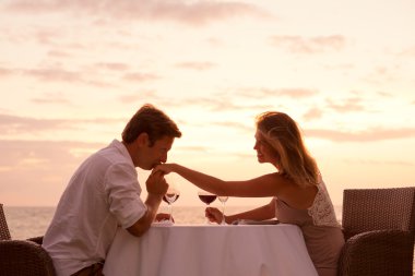 Couple enjoying romantic sunnset dinner on the beach clipart
