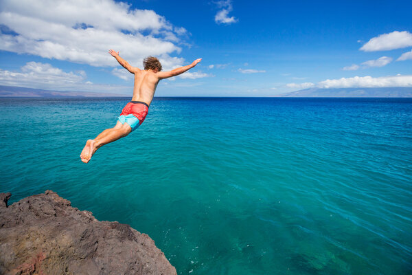 Человек, прыгающий со скалы в океан
