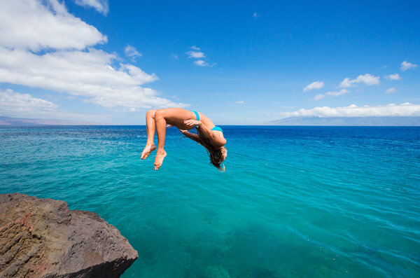 Woman doing backflip into ocean