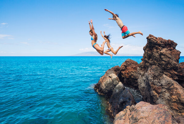 Friends cliff jumping into the ocean