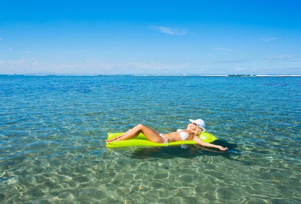 Woman floating on raft in tropical ocean — Stock Photo, Image