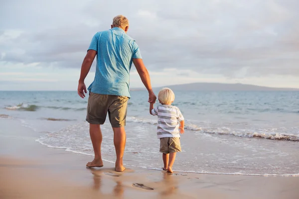 Vader en zoon wallking op het strand — Stockfoto