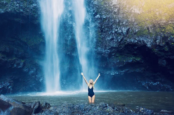 Woman in pool at base of large watefall — Stock Photo, Image