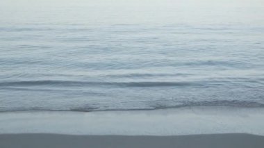 Yaz güneşinde huzurlu denizden gelen beyaz kumlu ve sakin dalgalı sahil. Yaz tatilinde doğa konseri.