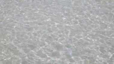 Dalganın yüzey dokusu, yaz güneşinde, beyaz kumsaldaki sakin denizden geliyor. Yaz tatili doğası