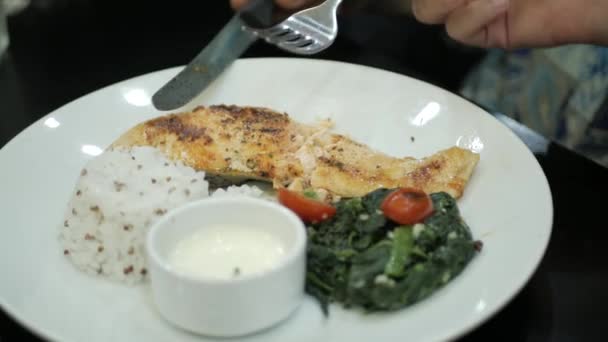 レストランで夕食を食べる サーモンフィッシュステーキをナイフとフォークで切る 健康的な食事と食事のコンセプト — ストック動画
