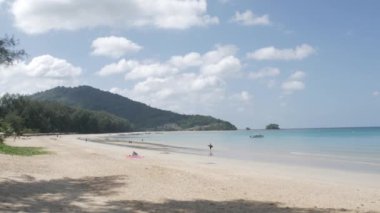 December 28,2021: Phuket,Thailand: people relaxing on the white sand beach with wave from peaceful sea in sunshine daytime