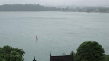 aerial view to a man while sailing in the sea when it is raining in phuket siray bay sea