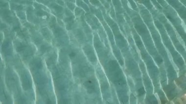 Yüzme havuzundaki suyun yüzey görüntüsü. Güneş ışığı yüzeye yansıyor.