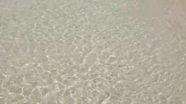Dalganın yüzey dokusu, yaz güneşinde, beyaz kumsaldaki sakin denizden geliyor. Yaz tatili doğası