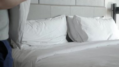 Otel servisi konsepti, temizlikçi, yastığı beyaz çarşafla yatır, sabah yatağı topla.