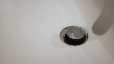 Musluktan beyaz lavaboya akan suyu aç ve kapat.