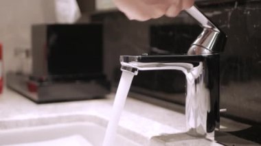 Musluktan akan suyun altında ellerini yıkamak.