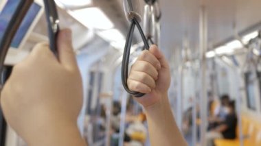 Metro, toplu metro taşımacılığı treninde tırabzan ya da kayışları tutan ellere yakın çekim.