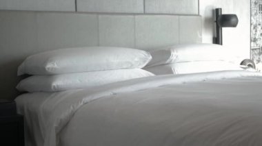 Otel servisi konsepti, temizlikçi, yastığı beyaz çarşafla yatır, sabah yatağı topla.