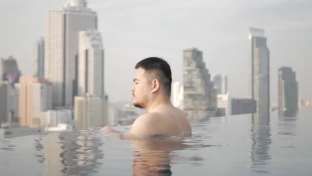 Asian Man While Relaxing Infinite Swimming Pool Background City Sunset — 图库视频影像