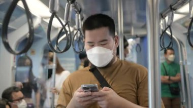asian man using smartphone while in public subway transportation