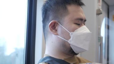 POV to a man wearing mask while ridding subway public transportation in Bangkok