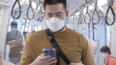 asian man using smartphone while in public subway transportation