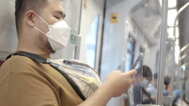 asian man using smartphone while in public subway transportation