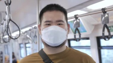 POV to a man wearing mask while ridding subway public transportation in Bangkok