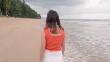 slowmotion of young adult lady relaxing walking on the beach with sea wave in summer day vacation