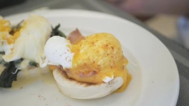 using spoon and fork cutting the egg benedict. Healthy Breakfast meal