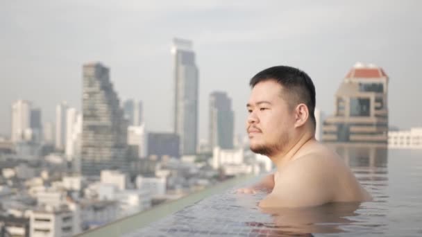 Asian Man While Relaxing Infinite Swimming Pool Background City Sunset — 图库视频影像