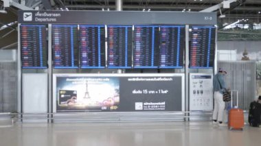 Mayıs 12,2022: Bangkok, Tayland: Suwannabhumi uluslararası havaalanında uçuş kurulu bilgilerine bakan, uçuşları kontrol eden insanlar. Havaalanı terminali uçuş saatinde turistler. Ülke yeniden açılıyor