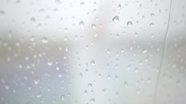 Uçağın penceresindeki yağmur damlası içeriden geliyor. Bulutlu yağmurlu hava koşulları.