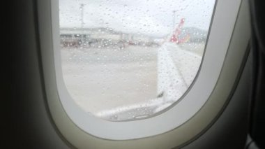 Uçağın penceresindeki yağmur damlası içeriden geliyor. Bulutlu yağmurlu hava koşulları.