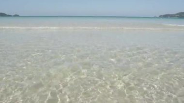 Dalganın yüzey dokusu, yaz güneşinde, beyaz kumsaldaki sakin denizden geliyor. Yaz tatili doğası