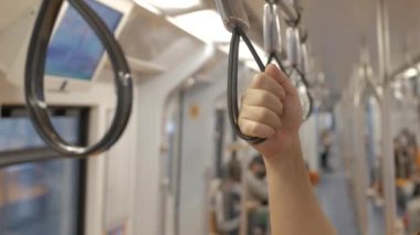 Metro, toplu metro taşımacılığı treninde tırabzan ya da kayışları tutan ellere yakın çekim.