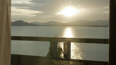 Sahildeki balkon tatil köyünden dağ sıraları ve deniz üzerinde gün batımı manzarası. Seyahat yerleri. Yaz tatili