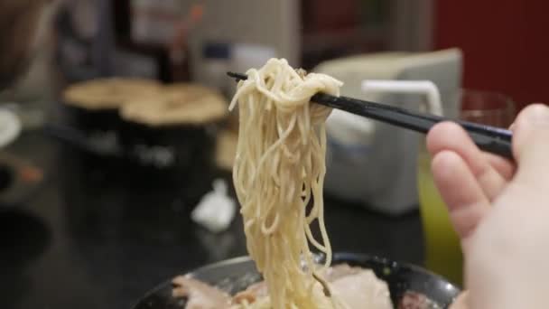 男は箸でラーメン日本の麺を食べます 豚スライス付きの日本のファーストフードラーメン — ストック動画