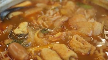 close up while using chopstick pick squid from Korean Kimchi tteok pokki soup with mussels, fish Ehmook, seafood and vegetable. Asain korean traditional food