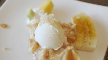 using fork to eat croffle waffles on plate with ice-cream and caramel banana. dessert plate