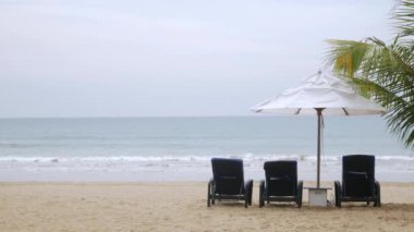 Luxury beach lounge beds with umbrella on white sand beach with coconut tree in thailand with sunny summer weather and clear blue sky