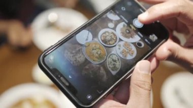 Yemek saatinde yemek yerken cep telefonuyla fotoğraf çekmek.