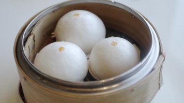 hand while picking chinese cream bun dimsum from basket steamer in chinese restaurant