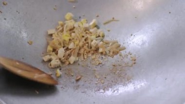 White Asian noodle and tofu while being cooked and stir fried in the pan preparing to make Pad-Thai