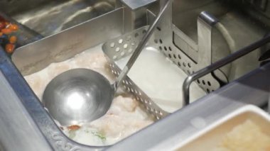 using soup ladle to take boiled szechwan hotpot chinese style cuisine asian soup. dinning in chinese restaurant