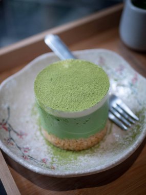 green tea mousse with matcha green tea topping in a plate in minimal japanese style cafe
