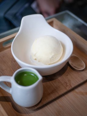 ice cream vanilla flavor with matcha green tea topping in a bowl cup in minimal japanese style cafe